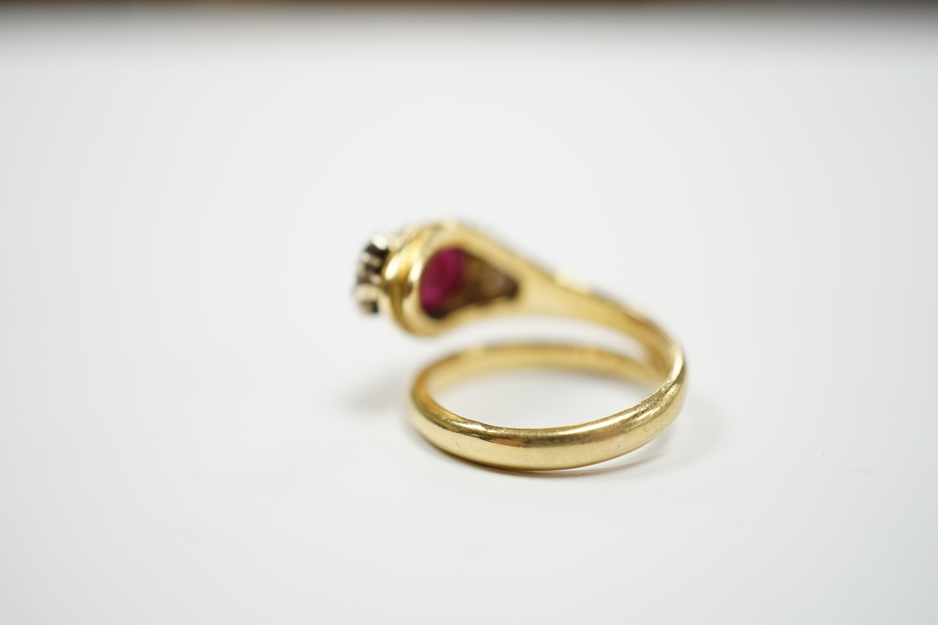A modern Italian 750, synthetic cabochon ruby and diamond chip set coil shank dress ring, size J/K, gross weight 6.9 grams.